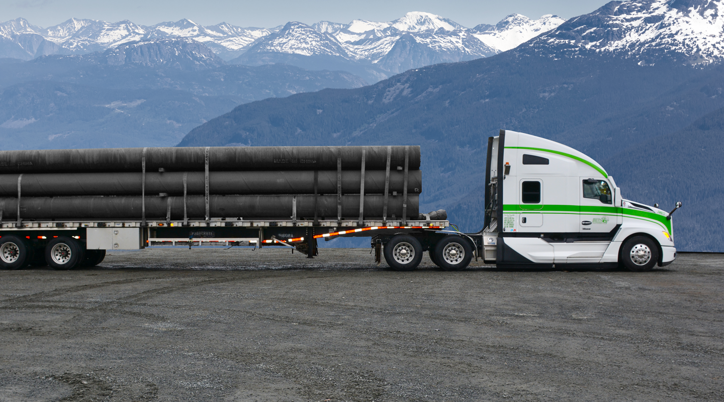 Side view of Seven Horses flat deck truck hauling specialized freight in front of Western Canada landscape