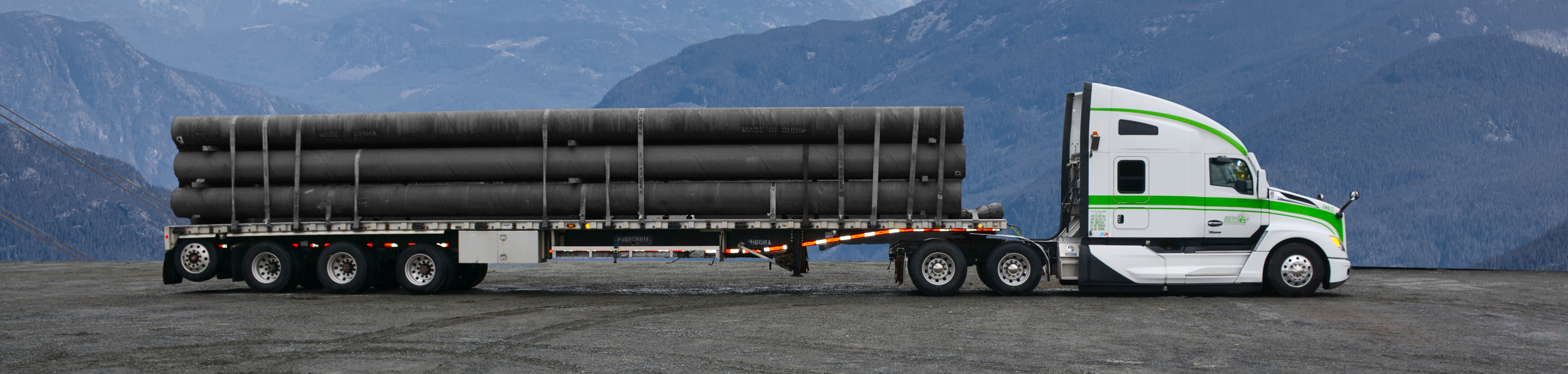Side view of Seven Horses flat deck truck hauling specialized freight in front of Western Canada landscape